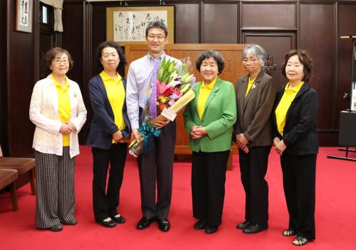 宮崎県地域婦人連絡協議会の皆さまと、贈呈された花束を抱える知事の写真