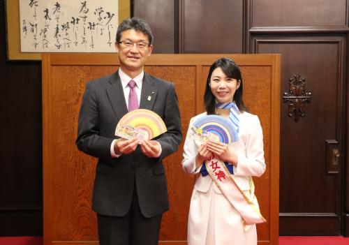 宝くじ券を手にした知事と宝くじ幸運の女神のツーショット写真