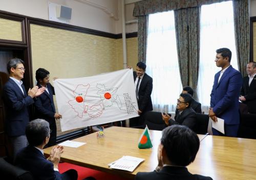 バングラデシュと宮崎の友好を表した旗を披露する様子の写真