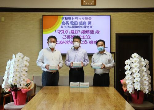 寄贈されたマスクを手にした、宮崎県トラック協会の皆さんと知事の写真